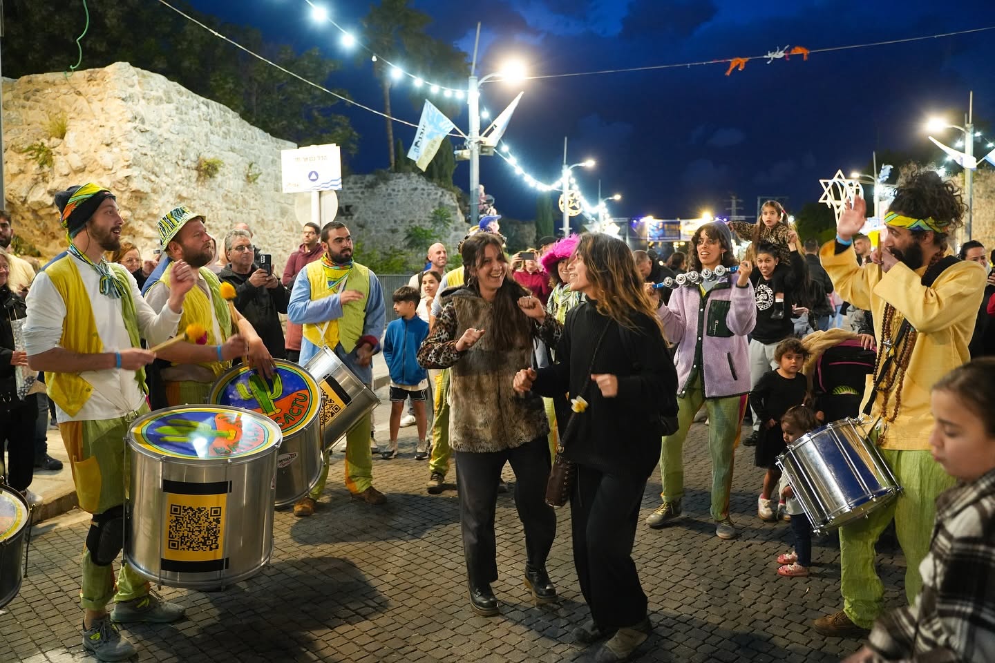 Percussionists lead a procession through the city streets at night.