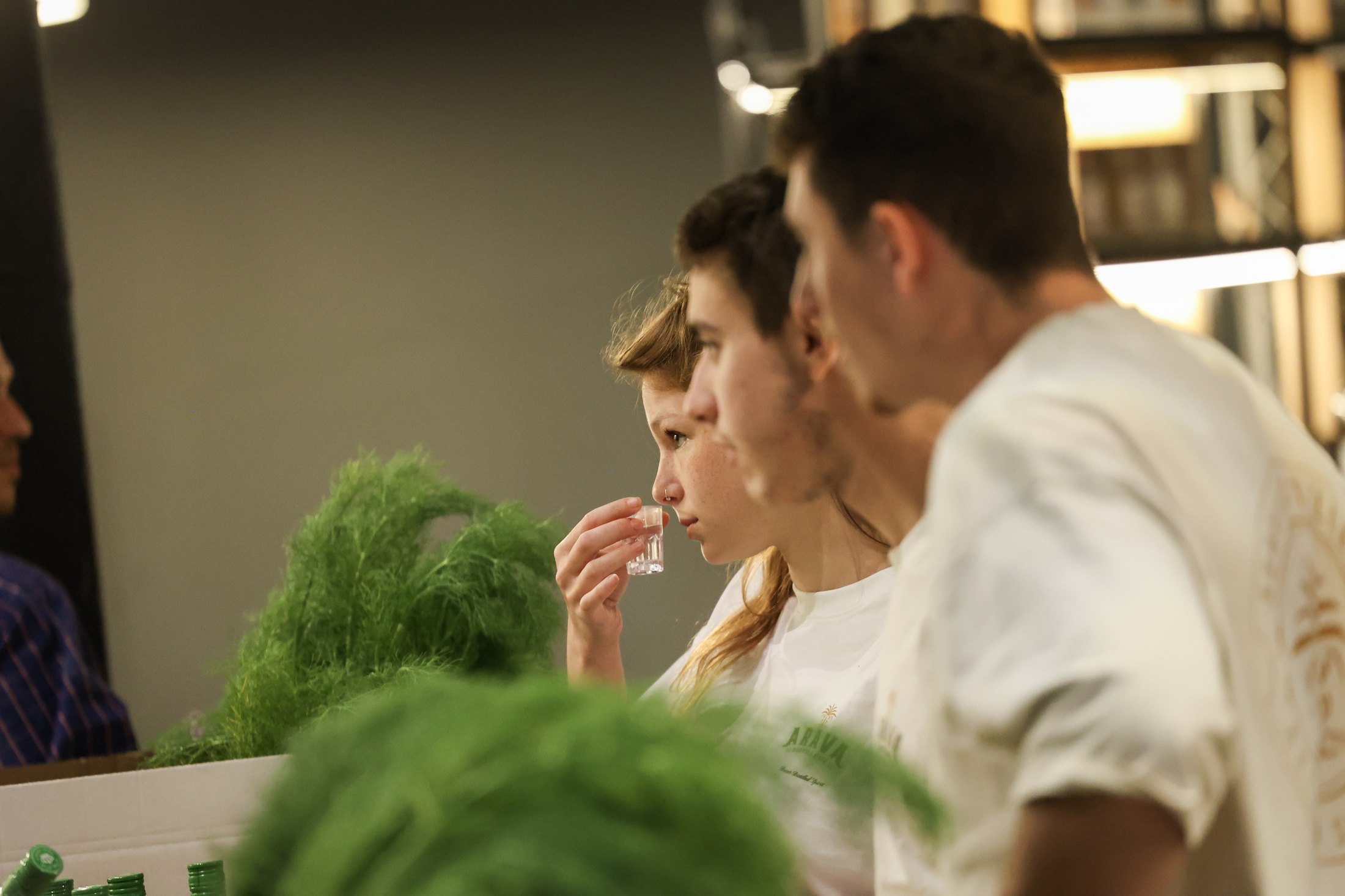 Visitors taste drinks among plants and exhibition stands.