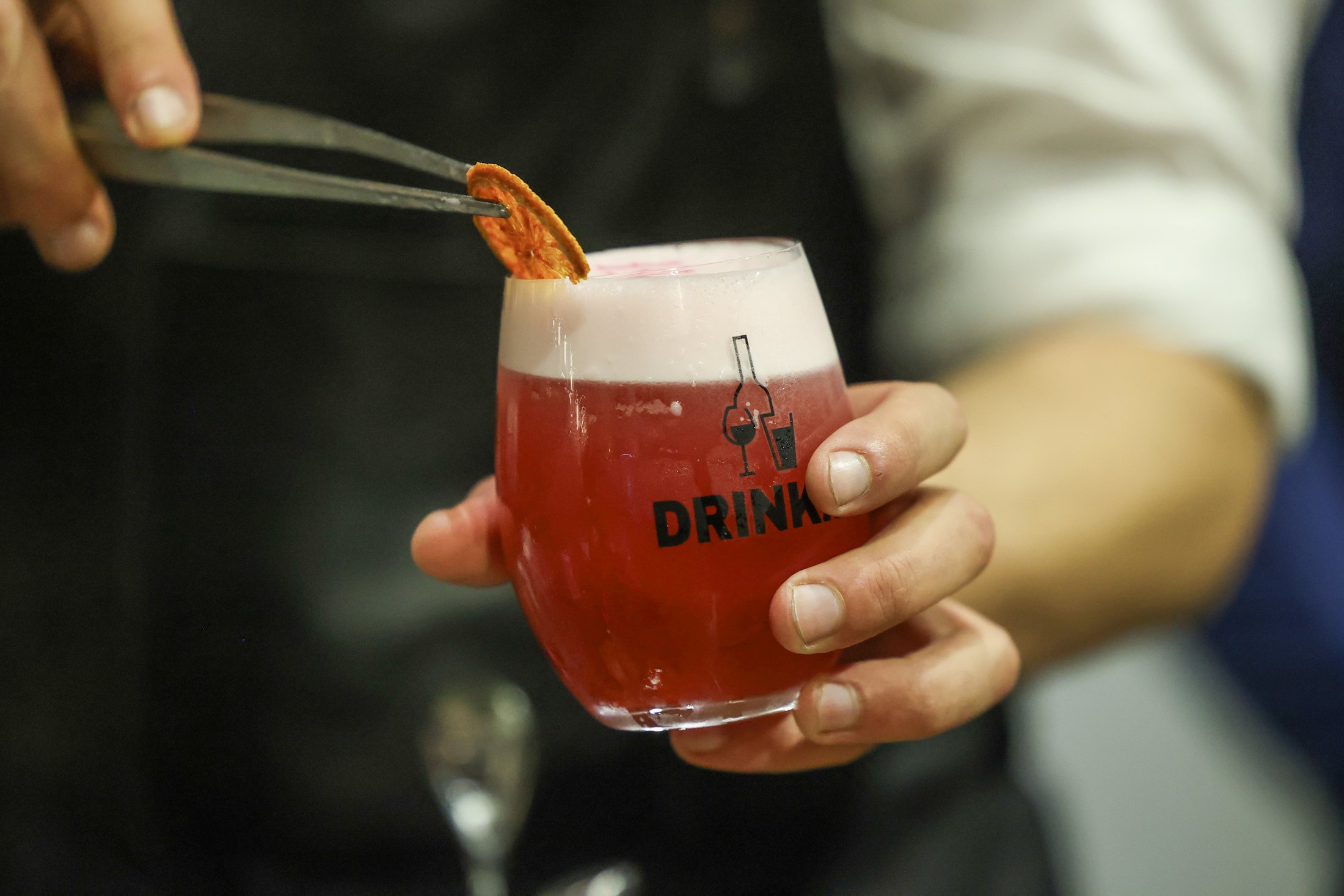 A red drink is poured into a glass marked DRINK.