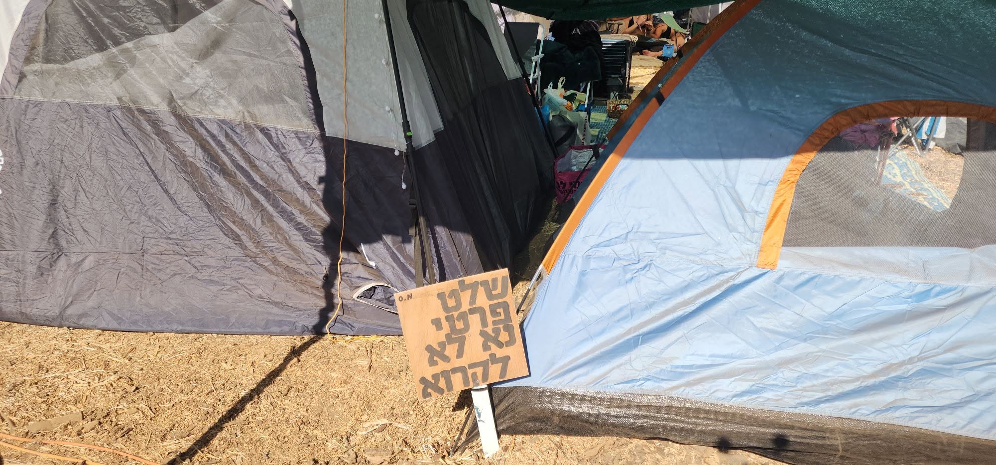 A small hand-lettered sign hangs beside a tent entrance.
