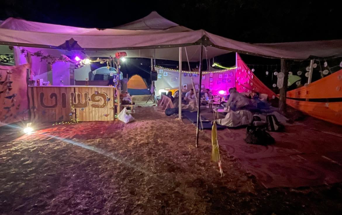 A pink-lit seating area beneath a shade canopy.
