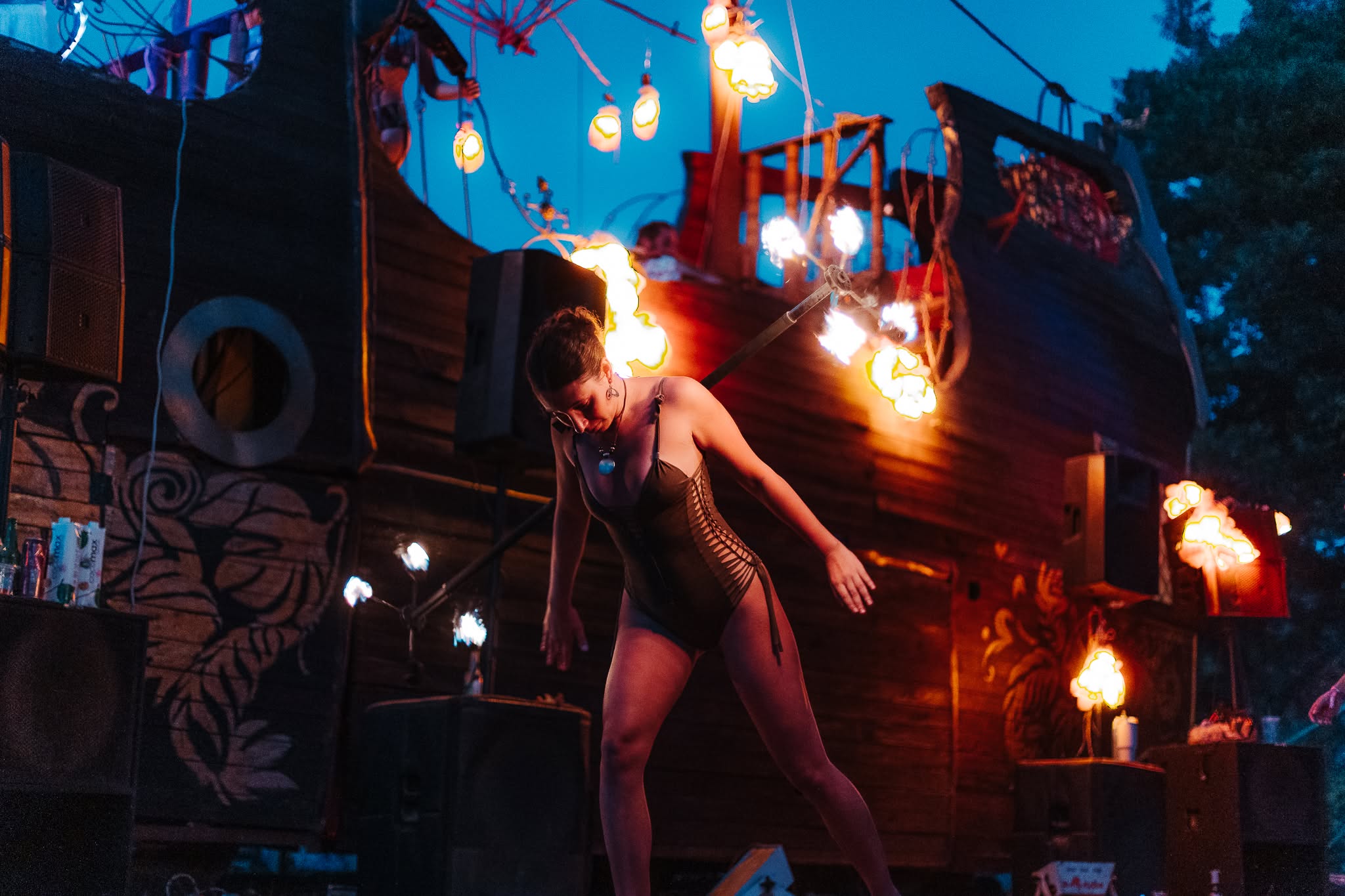 A woman performs with fire beside a decorated structure at night.