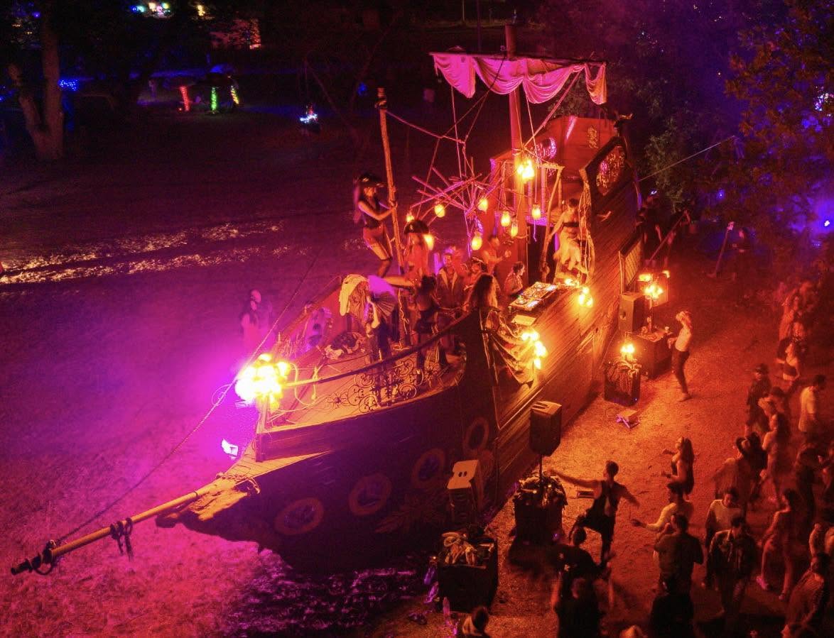 A boat-like installation glows red and orange at night.