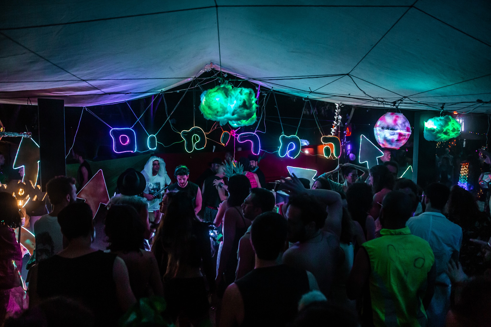 A crowd dances beneath a canopy and glowing cloud installations.
