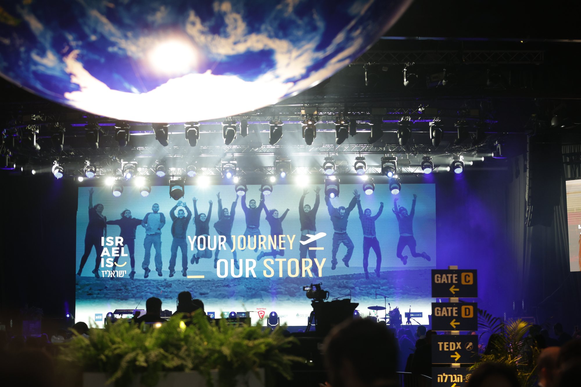 Main stage before a crowd, with a screen bearing the Israel-is slogan.