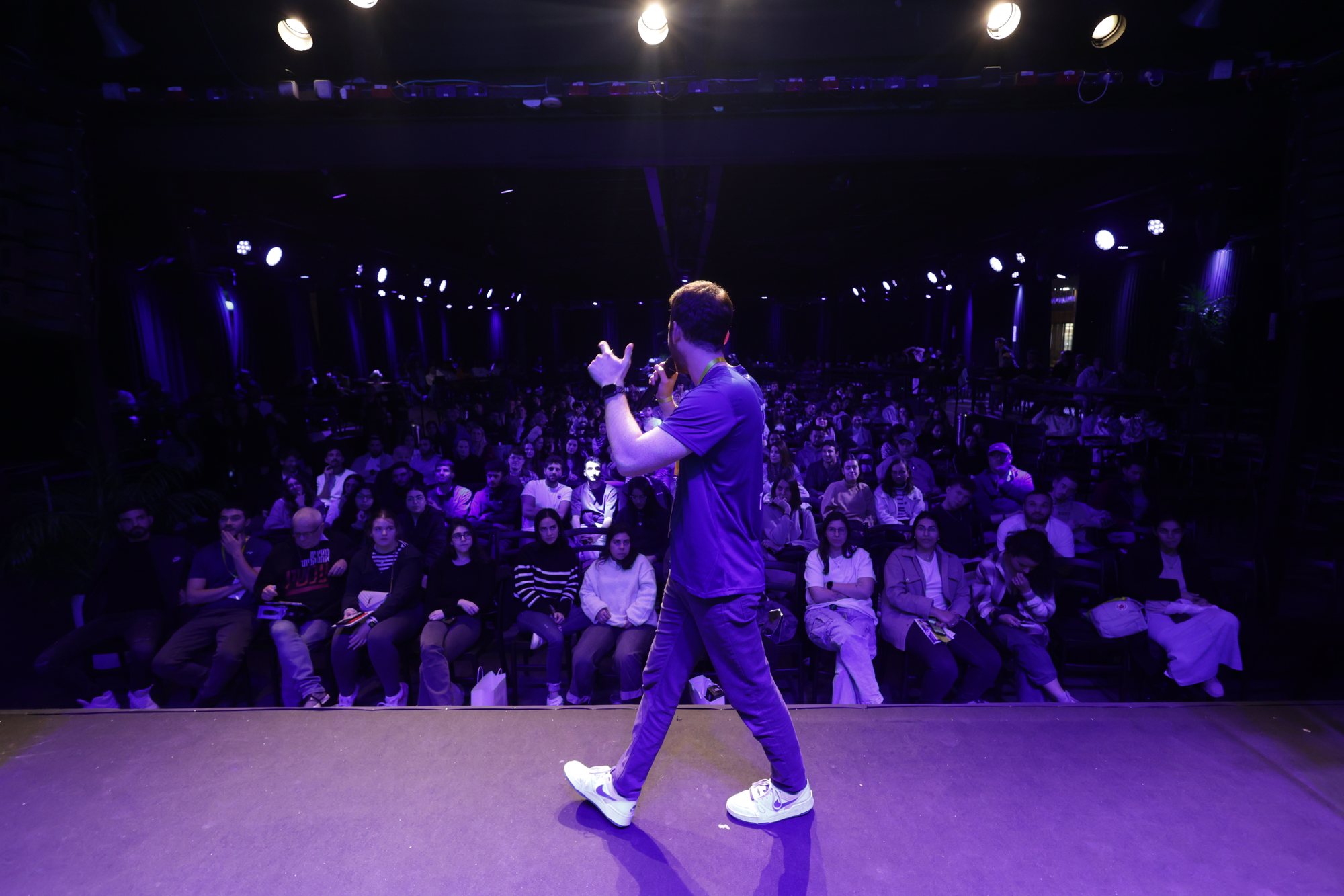 A speaker stands on stage before a large audience.