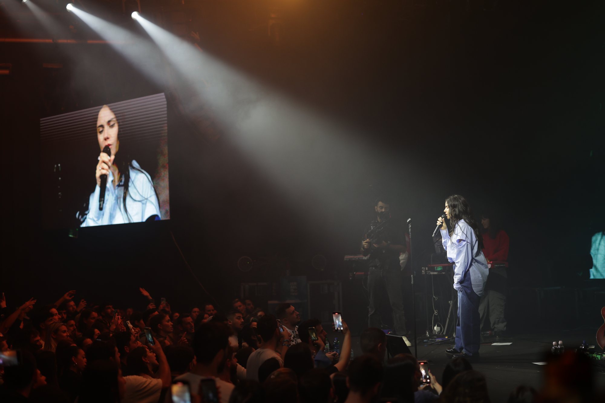 A singer performs on stage and appears on a large screen.