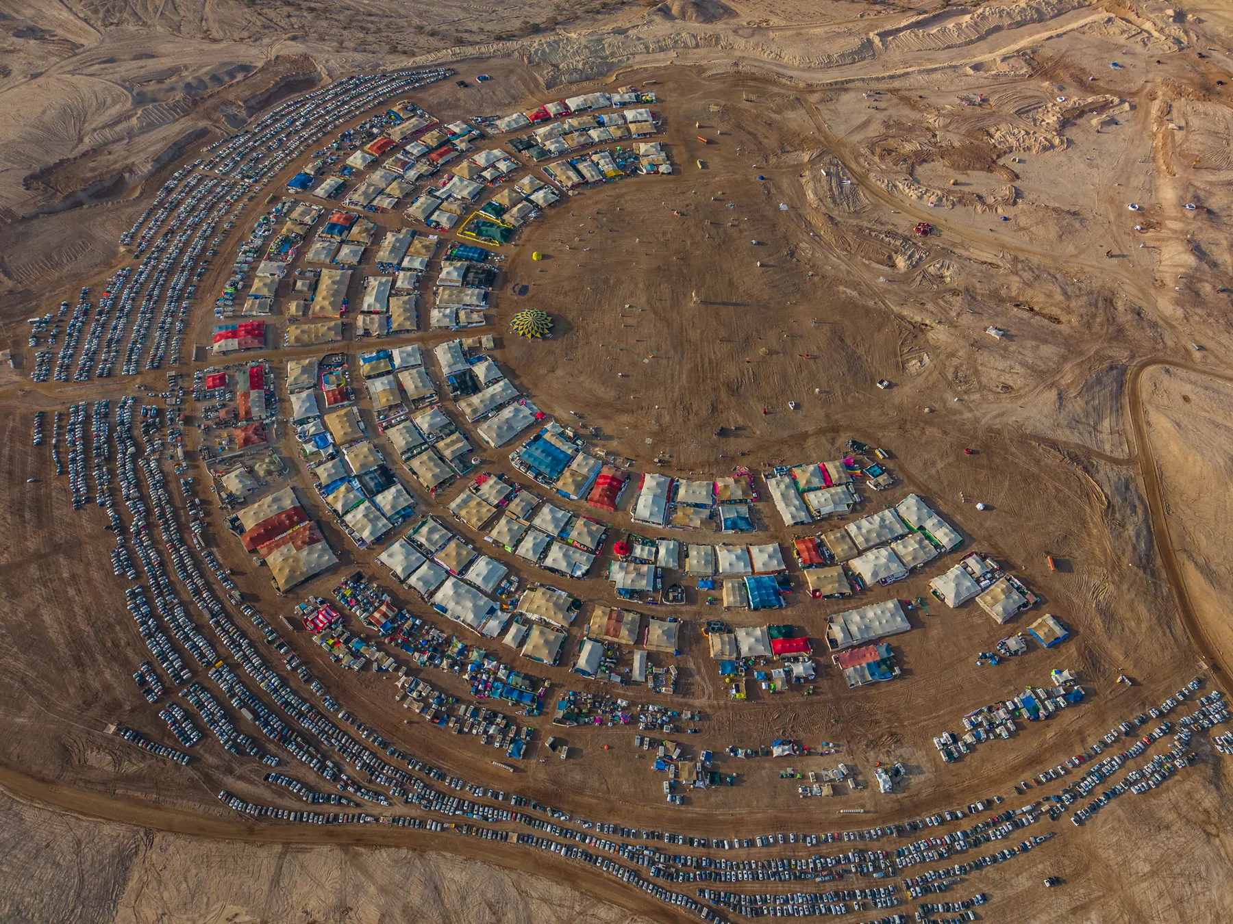 Daytime aerial view of Midburn camps arranged in arcs across the desert.