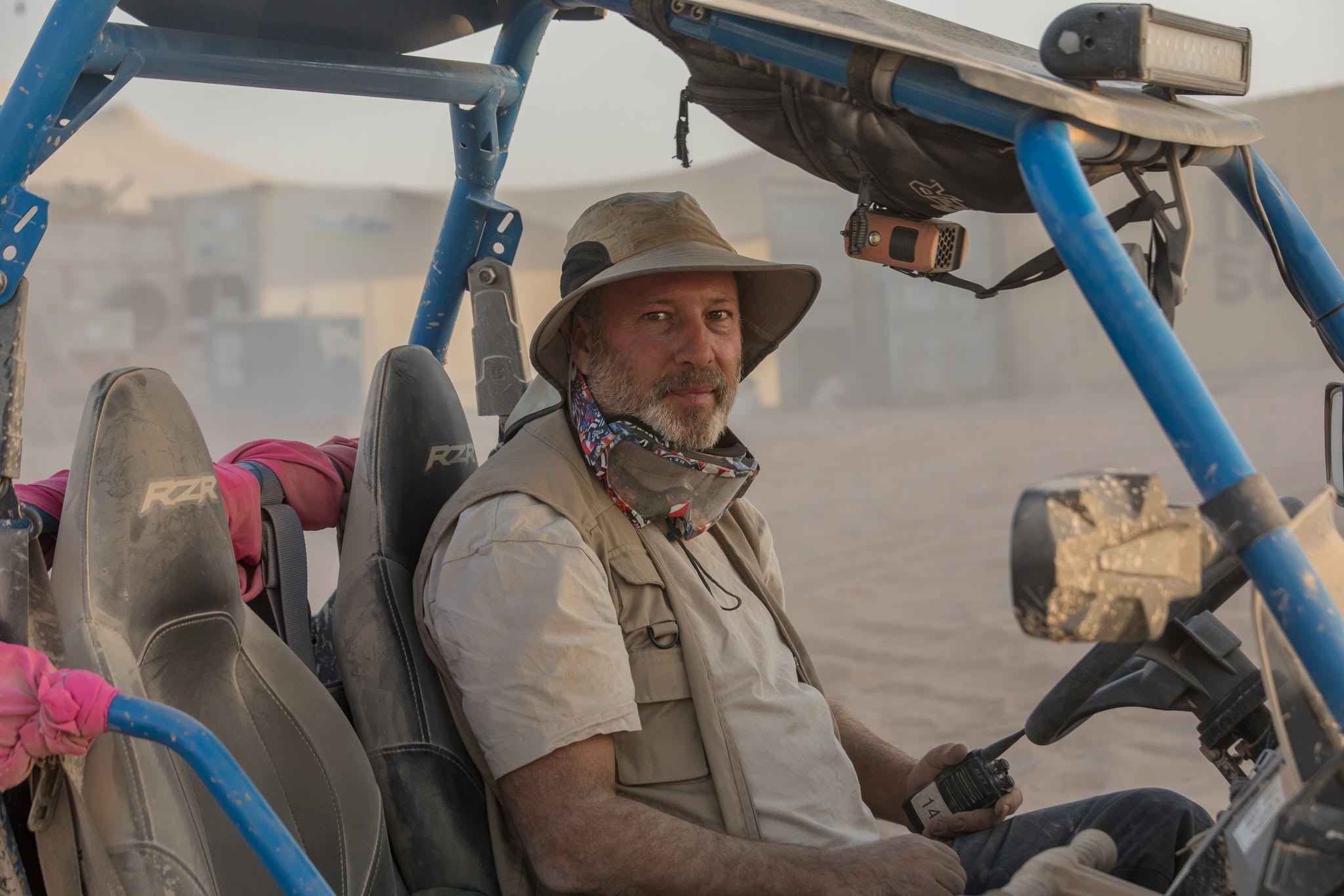 A person seated in an open off-road vehicle in the desert.