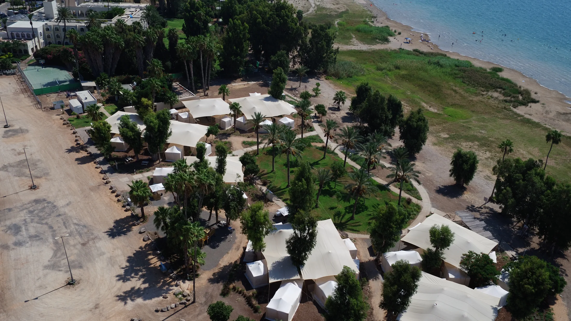 Aerial view of tents and lawns along the Sea of Galilee shore.