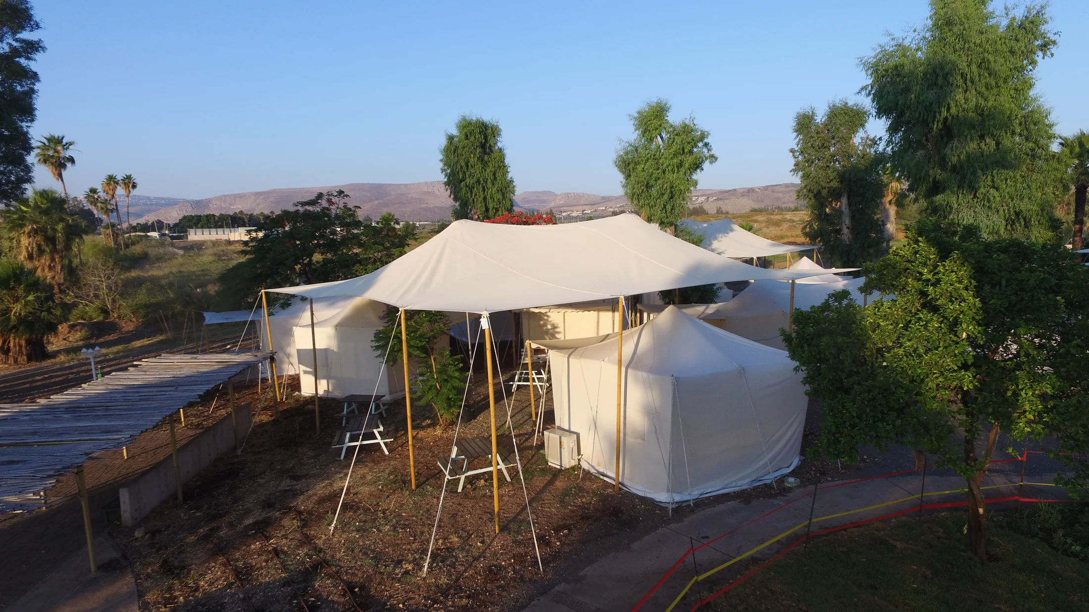 A white guest tent beside an access path and plants.