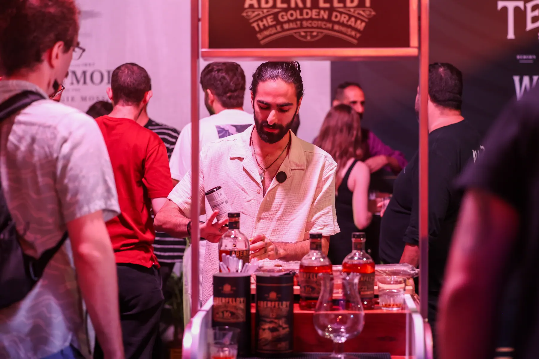 A bartender prepares a drink behind a whisky stand.