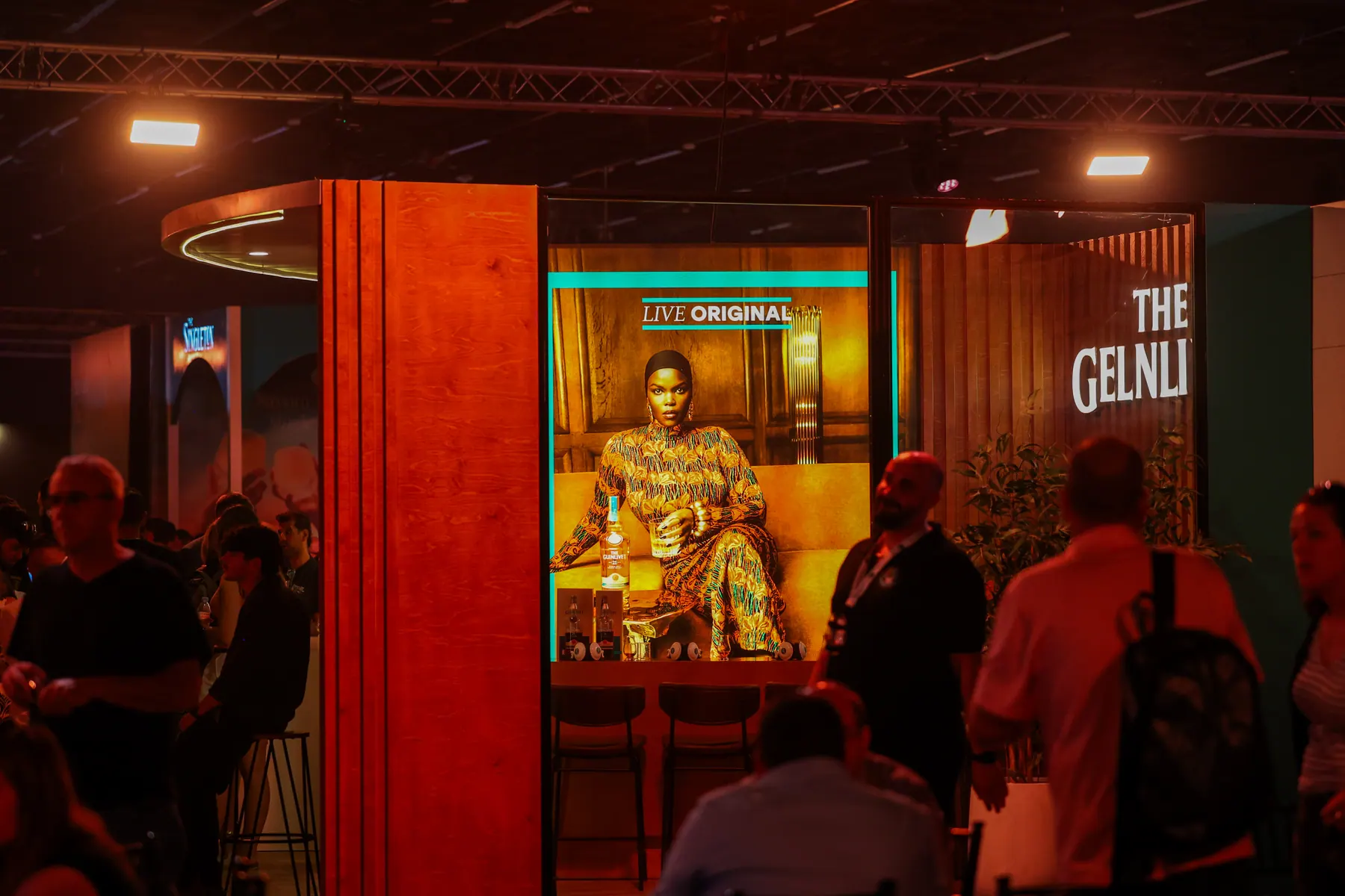 An illuminated whisky stand with visitors in front of it.