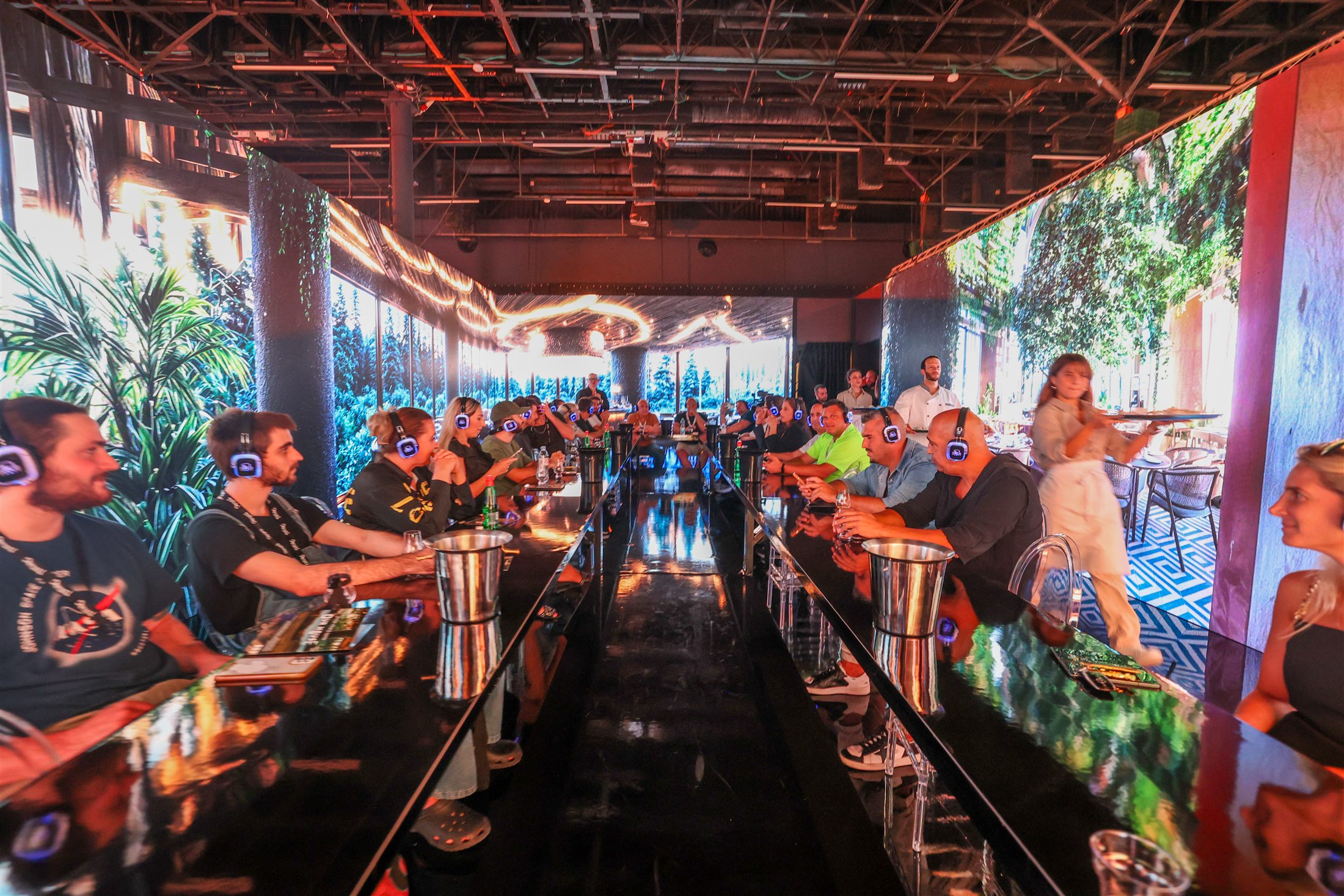 A row of illuminated bars and visitors inside the exhibition hall.